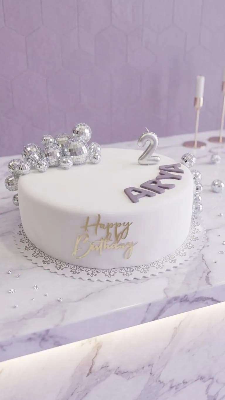 Weiße Torte zum zweiten Geburtstag mit silbernen Kugeln und Namen