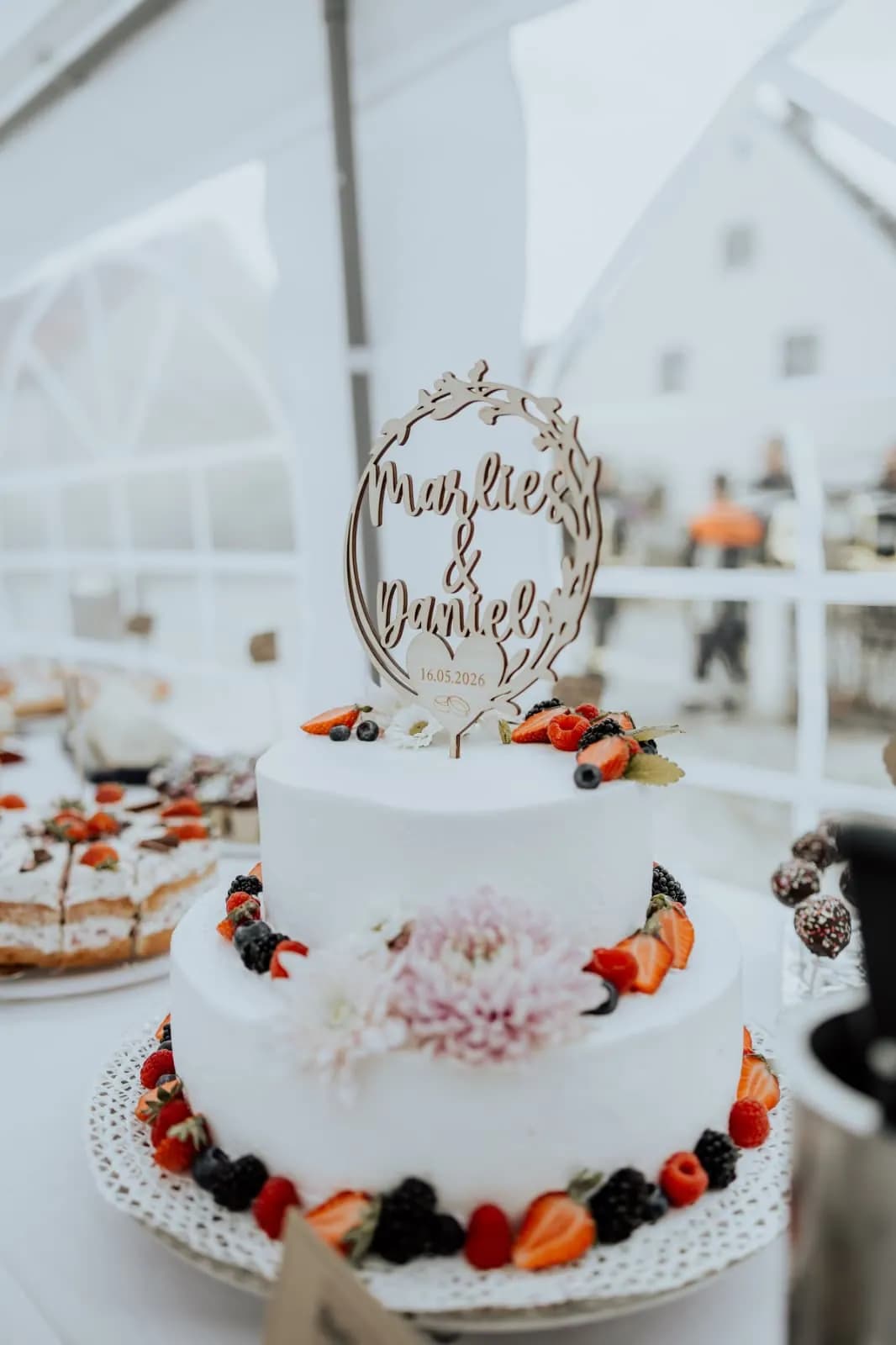 Zweistöckige Hochzeitstorte mit Beeren und Chrysantheme im Festzelt