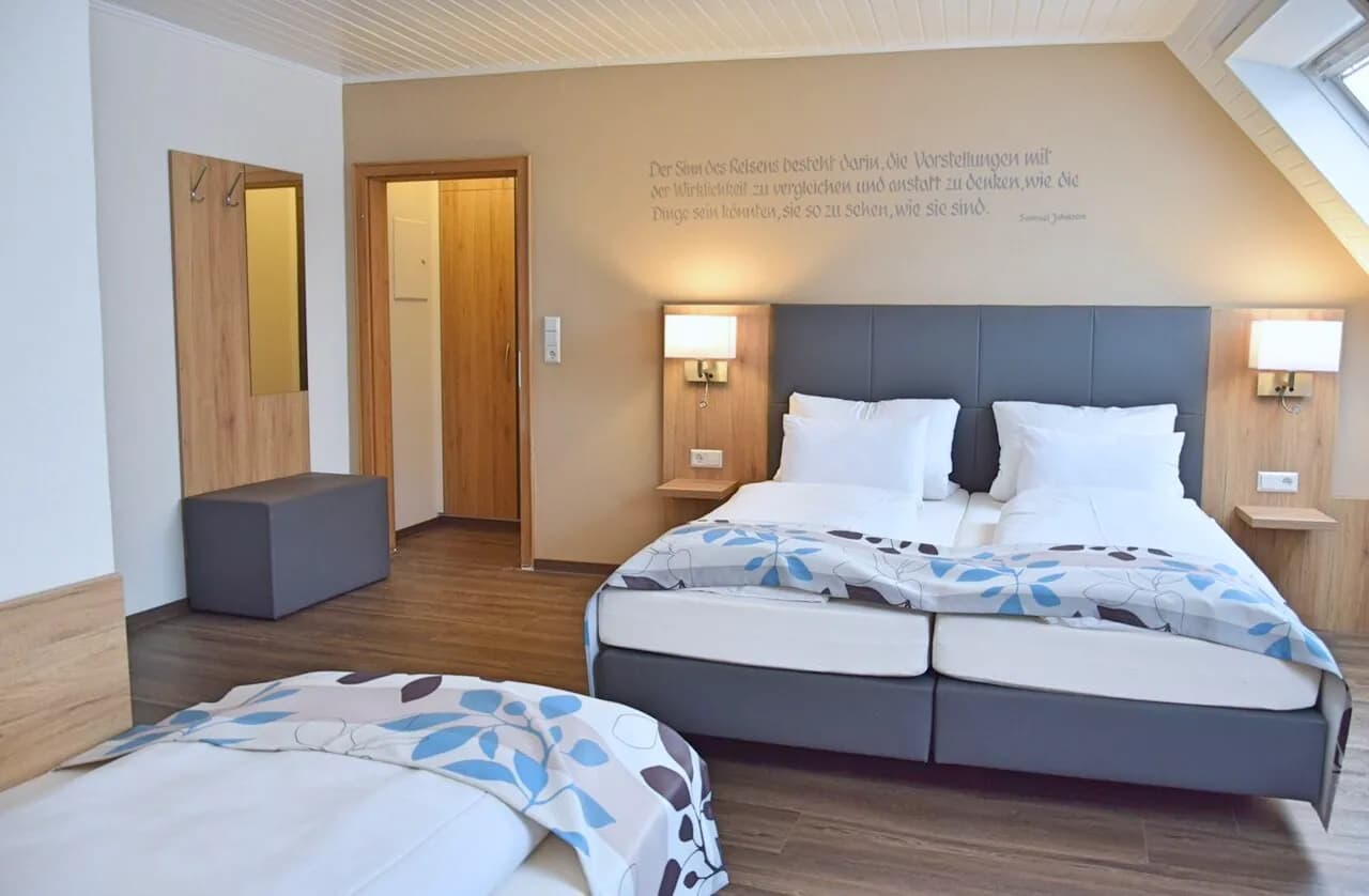 Doppel-Dreibettzimmer: Doppelbett mit Leselampen unter der Holzdecke