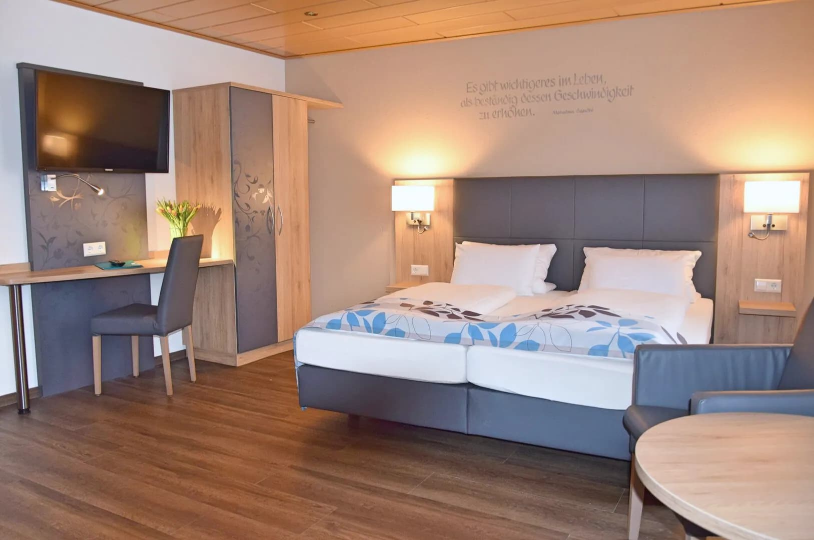 Doppel-Dreibettzimmer: Doppelbett, Schreibtisch, Sessel und runder Tisch